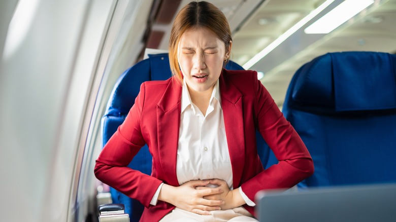 a woman with an upset stomach on a plane