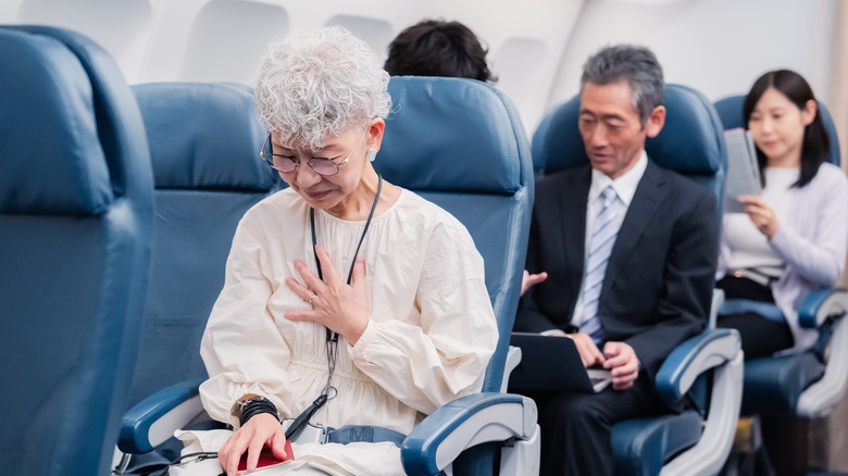 Woman clutching chest on plane