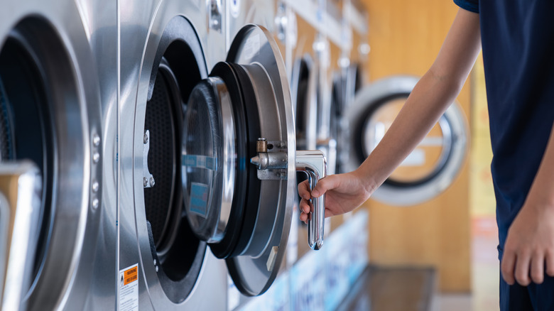 Person opening a door to a machine in a laundromat