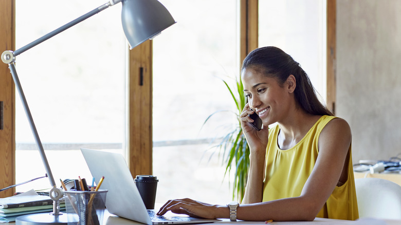 woman on phone in front of laptop