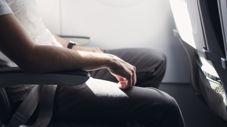 man's arm on airplane armrest