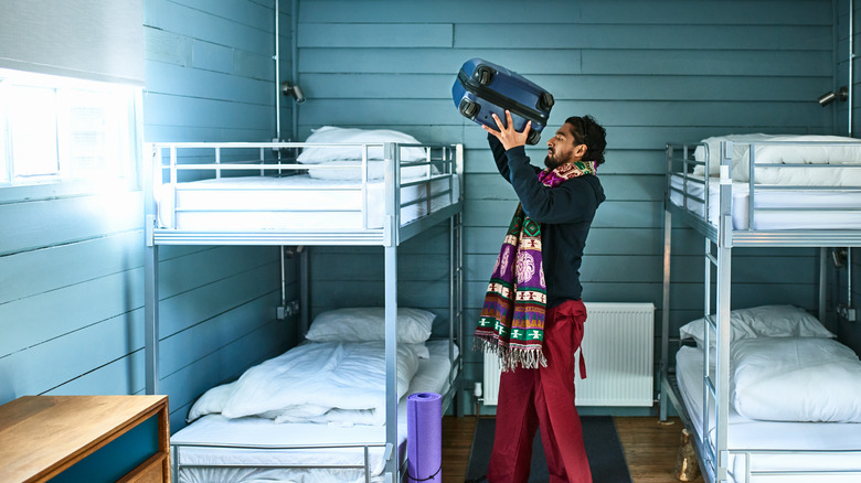 man puts suitcase on bunkbed