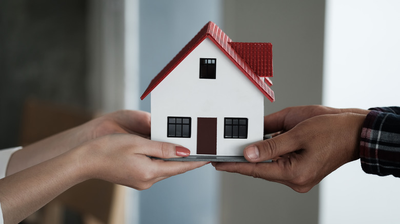 Hands exchanging a miniature home