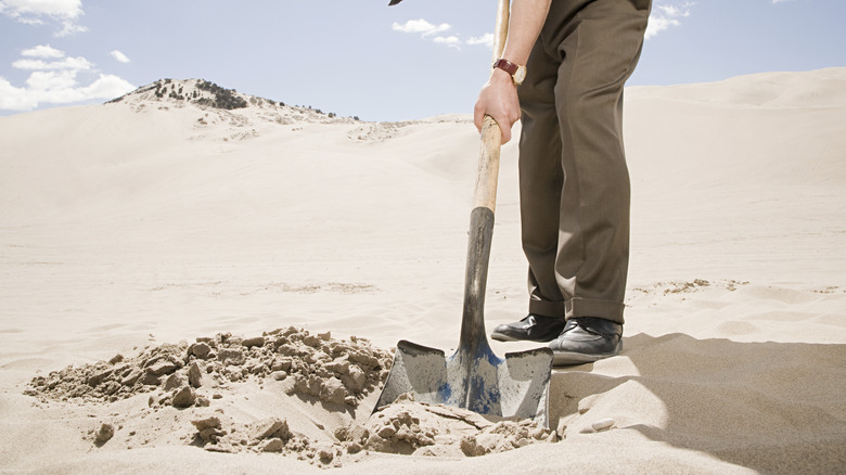 man digging hole in desert