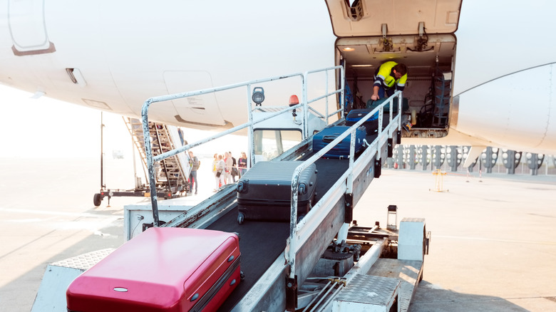 Loading airplane baggage into cargo on plane