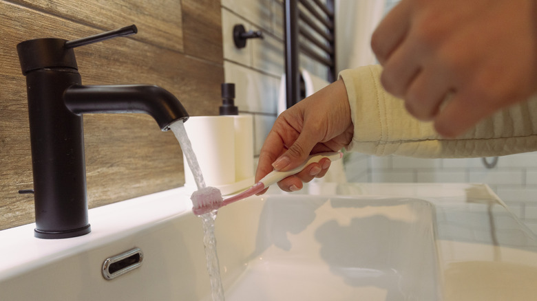woman wetting toothbrush with water
