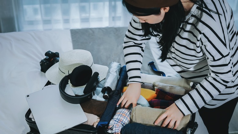 Woman rolling clothes in suitcase