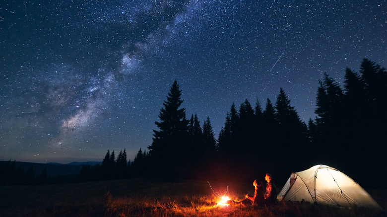 couple sitting outside tent at night stargazing