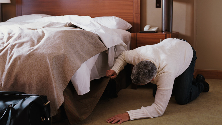 Person checking under hotel bed