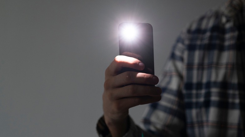 Person holding up phone with flashlight