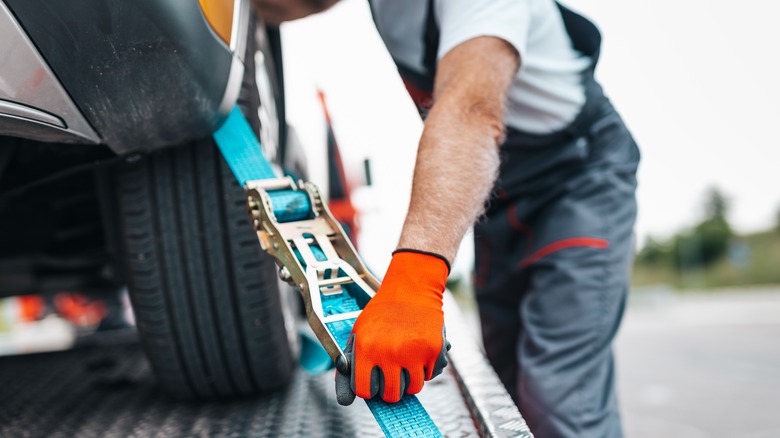 man with orange gloves towing car