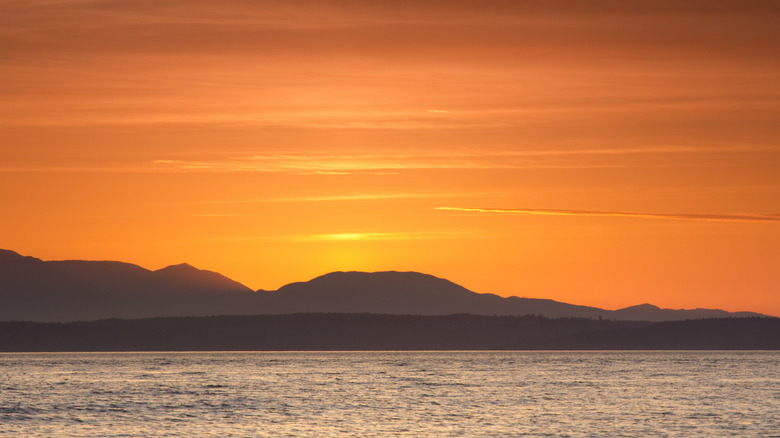 sunset behind mountains and water