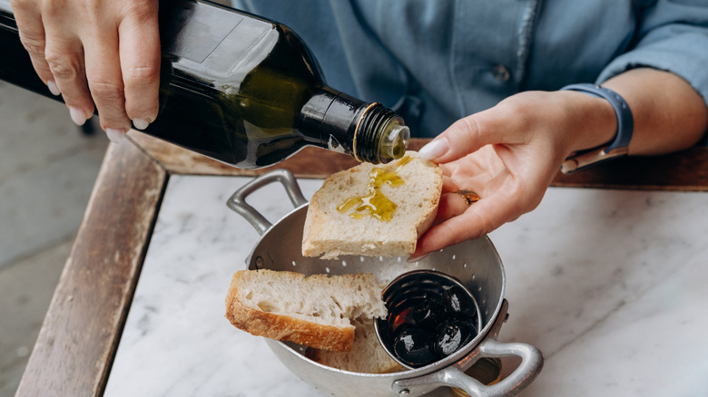 Woman adding olive oil to bread