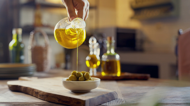 Adding olive oil to olives