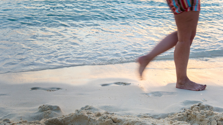 Beachgoer walking barefoot along the shore