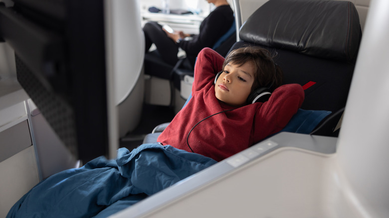 A child traveling unaccompanied relaxes wearing headphones.