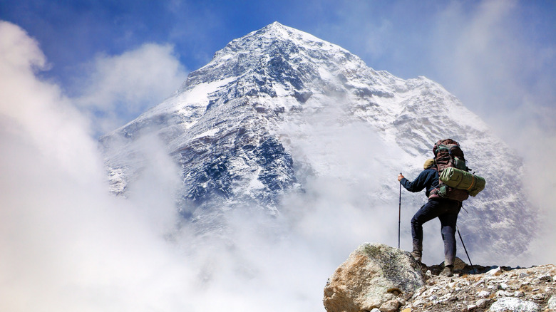 hiker with backpack and poles with mountain in background