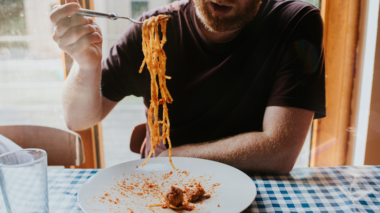 A man eating spaghetti with a fork