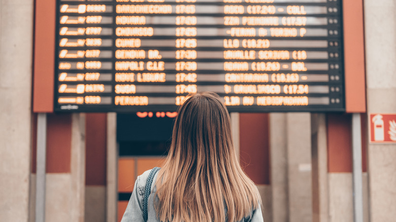 Woman looking at arrival and departure board at airport