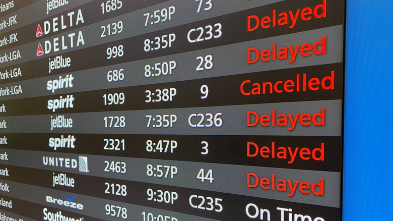 Departure board at airport showing delays and canceled flights