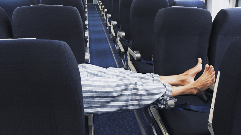 Person lying across the aisle on an airplane