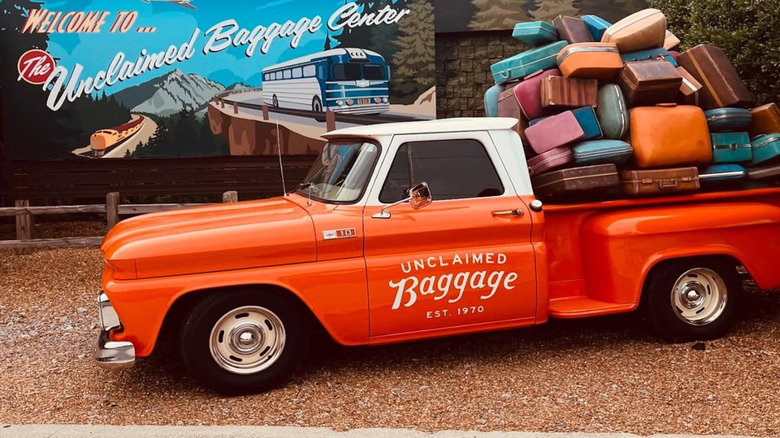 An orange pickup truck with stacks of suitcases in the truck bed