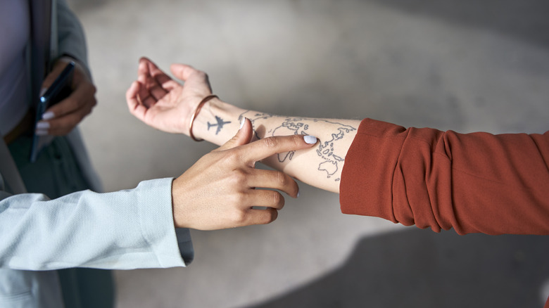 Hand pointing to world tattoo