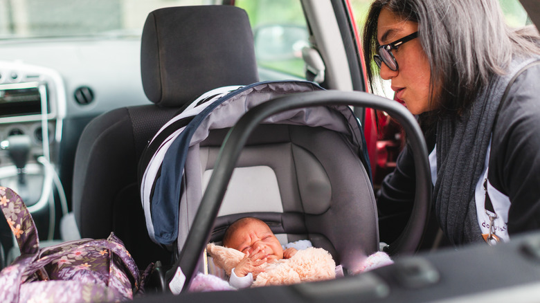 mother buckling newborn in car