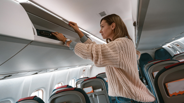 passenger stowing luggage on plane