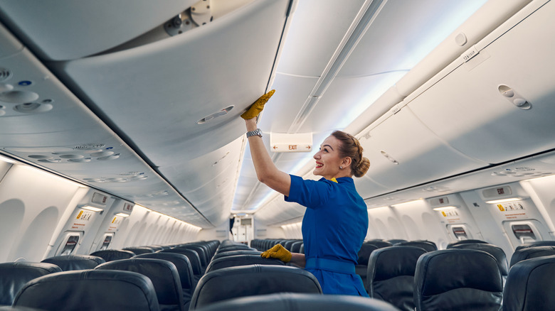 Flight attendant closing overhead bin