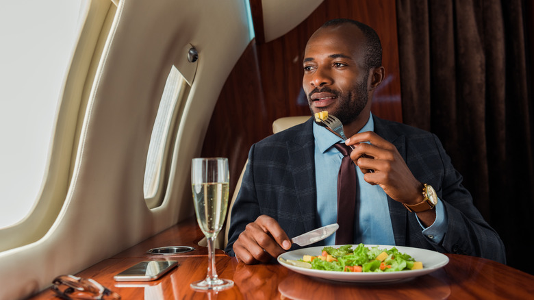 Man eating salad in business class