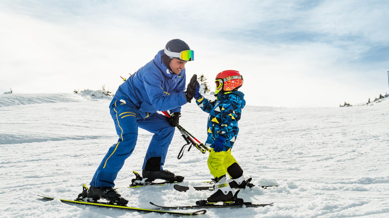 A ski instructor giving a young skier a high five