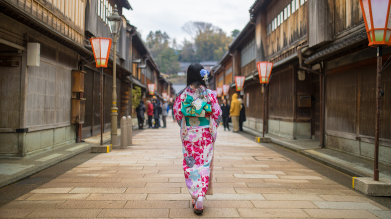 Woman in kimono walking down traditional Japanese street