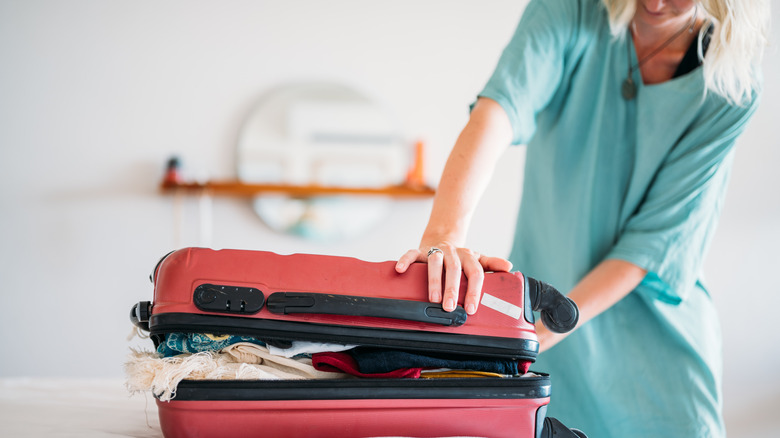 Woman closing a suitcase