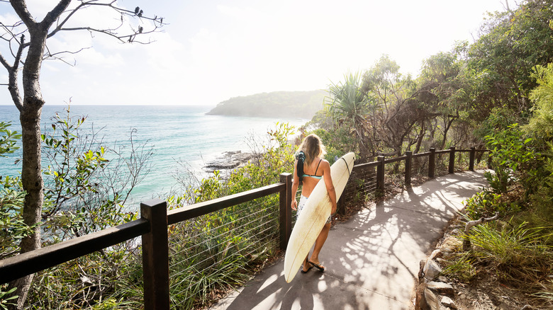 Woman walking with a surfboard 