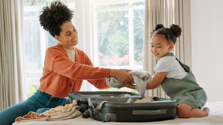 mother and daughter packing suitcase