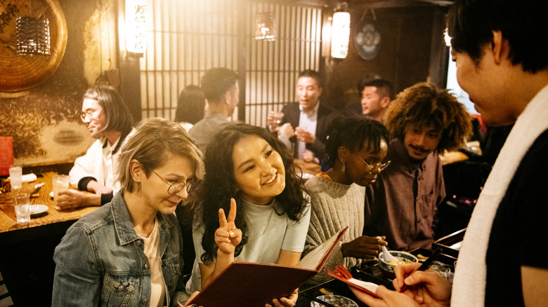 two women ordering food in a busy Japanese izakaya