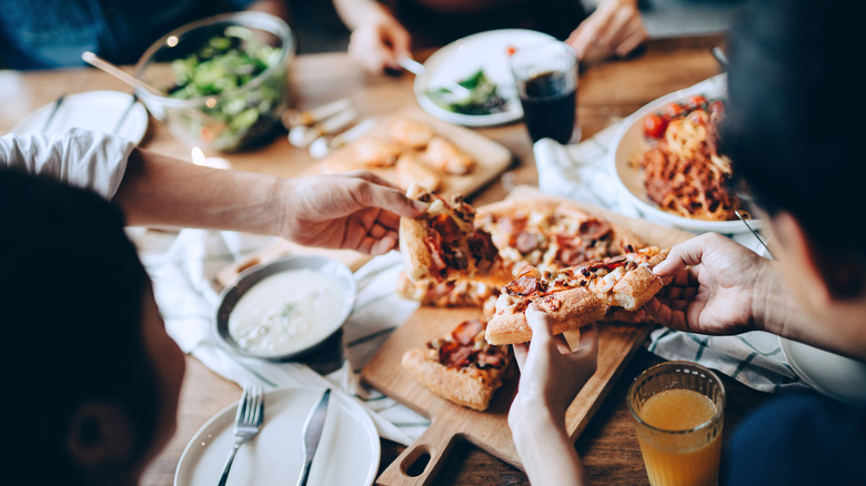 Friends sharing pizza at a restaurant close up shot