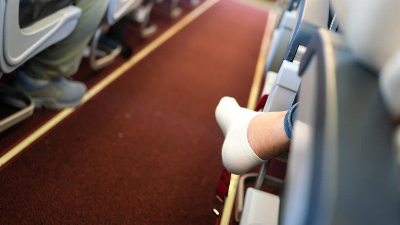 Shoeless plane passenger in aisle