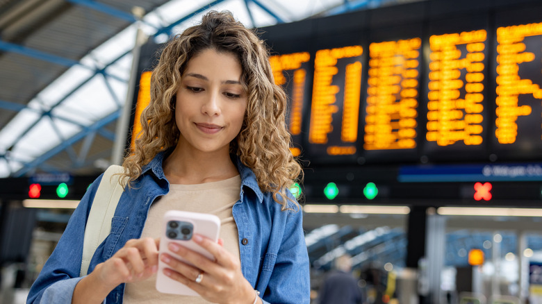 woman looking at phone in train station