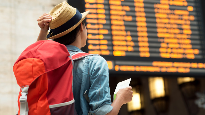 person with hat and backpack waiting at station