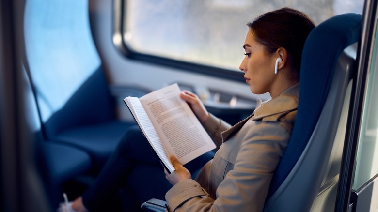woman reading a book on train