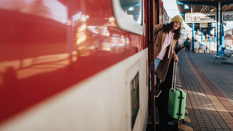 woman with suitcase exiting train