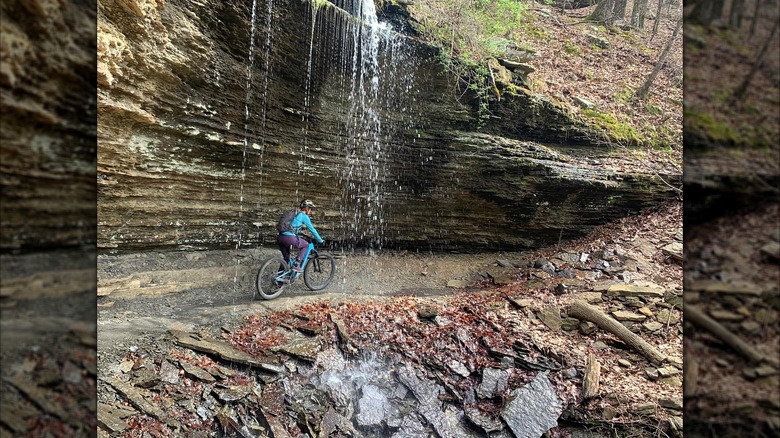 Mountain biker riding beneath waterfall