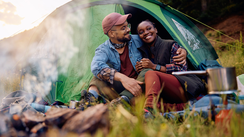 couple in front of tent by campfire