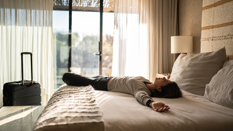 Woman resting on hotel bed