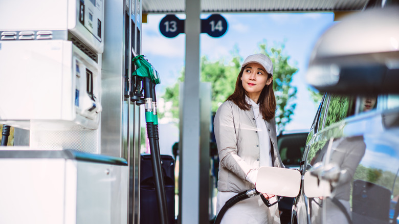 Woman pumping gas at station