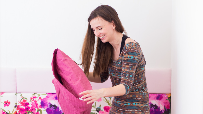 woman putting on pink pillowcase