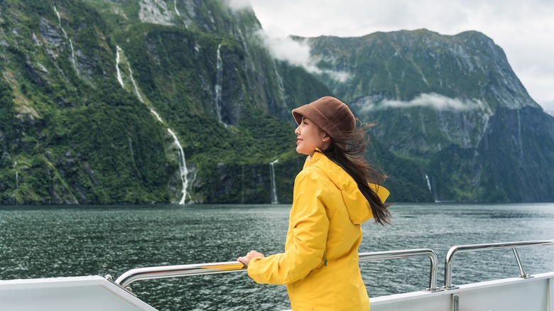 Woman gazes at cliffs from boat railing