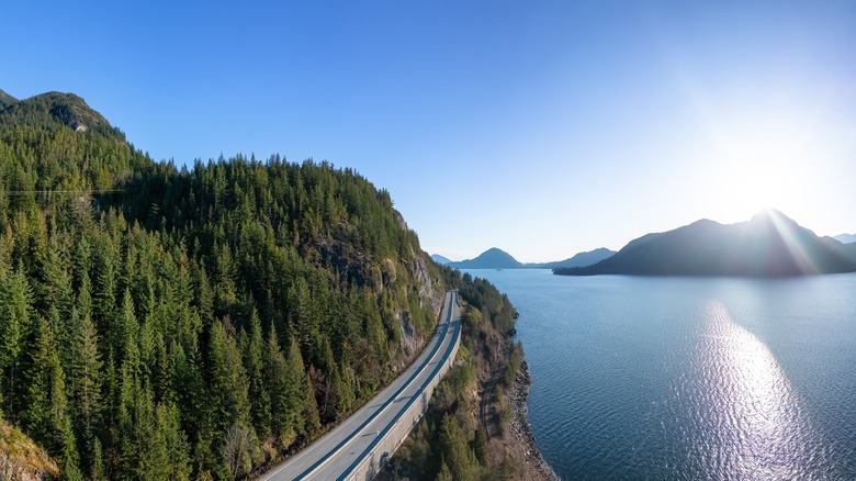 road in cliff by blue water